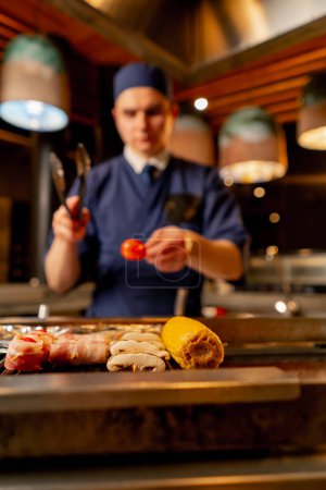 Téléchargez les photos : Dans un restaurant japonais, le chef grille divers légumes en accompagnement du poisson - en image libre de droit