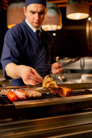 Téléchargez les photos : Dans un restaurant japonais, le chef grille divers légumes en accompagnement du poisson - en image libre de droit
