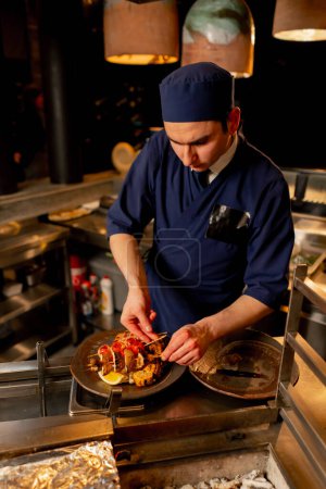 Foto de En el restaurante japonés el chef pone verduras fritas en un plato como guarnición para el pescado - Imagen libre de derechos