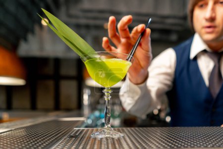 Foto de En el restaurante japonés en el mostrador del bar, el camarero pone los toques finales en un cóctel exótico - Imagen libre de derechos