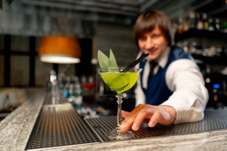 Téléchargez les photos : Dans un restaurant japonais le barman se tient sur le comptoir du bar offrant un cocktail prêt à l'emploi - en image libre de droit