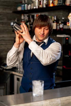 Photo for In a Japanese restaurant behind the bar the bartender shakes a cocktail in a shaker - Royalty Free Image