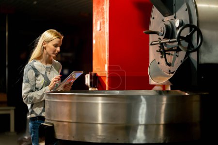 Foto de En la fábrica de tostado una inspección profesional comprueba la calidad del proceso de tostado del café - Imagen libre de derechos