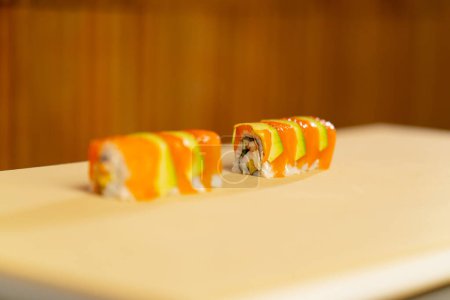 Téléchargez les photos : Gros plan dans un restaurant japonais poisson prêt à servir avec des sushis coupés à l'avocat - en image libre de droit