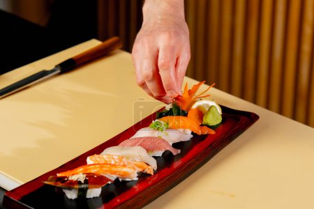 Foto de Primer plano en un restaurante japonés el chef decora piezas de pescado crudo en el plato - Imagen libre de derechos