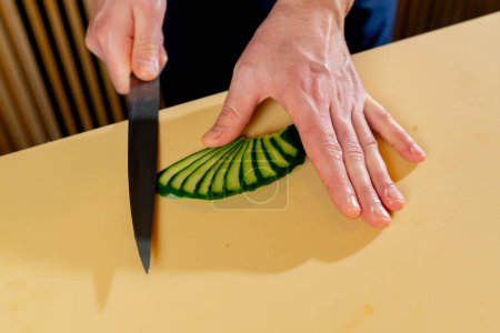Foto de Primer plano en un restaurante japonés el chef corta trozos de pepino para sushi - Imagen libre de derechos