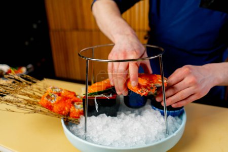 Foto de Primer plano en un restaurante japonés un chef en azul prepara un plato caro de mariscos - Imagen libre de derechos