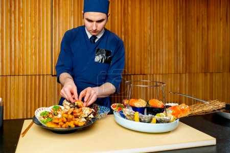 Foto de En un restaurante japonés un chef en azul prepara un plato caro de mariscos - Imagen libre de derechos