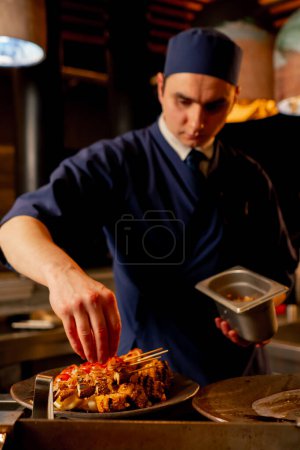 Foto de En un restaurante japonés el chef decora un plato de verduras fritas como guarnición para el pescado - Imagen libre de derechos