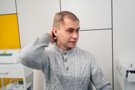Téléchargez les photos : Gros plan dans la clinique jeune homme dans un pull léger consulte un médecin oreille gorge nez - en image libre de droit