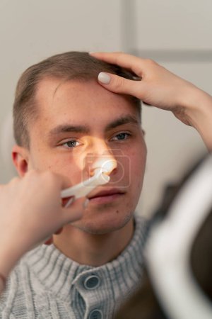 Photo for Close-up in the clinic a young doctor ear throat nose examines the patient s nose - Royalty Free Image
