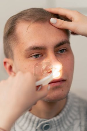 Foto de Primer plano en la clínica un médico joven oído garganta nariz examina la nariz del paciente - Imagen libre de derechos