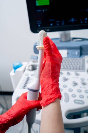 Téléchargez les photos : Gros plan la clinique gynécologique bureau échographie machine médecin met sur un préservatif - en image libre de droit