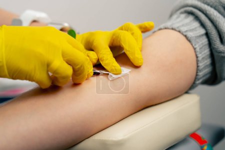 Photo for Close-up in the clinic a doctor in yellow gloves takes blood for tests from a patient - Royalty Free Image