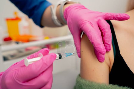 Téléchargez les photos : Gros plan dans une clinique privée dans la salle d analyse médecin fait un vaccin dans l épaule du patient - en image libre de droit