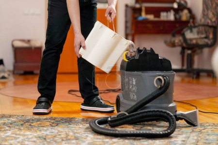 Foto de Limpieza profesional de un apartamento una limpiadora vierte detergente en una aspiradora - Imagen libre de derechos