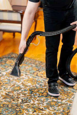 Téléchargez les photos : Dans l'appartement master cleaner arrose le tapis avec du détergent d'un aspirateur professionnel - en image libre de droit