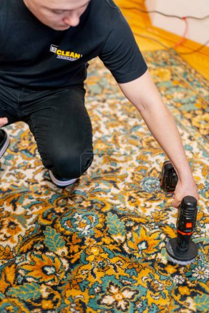 Photo for In the apartment a master cleaner cleans the carpet with detergent using a screwdriver and a brush - Royalty Free Image
