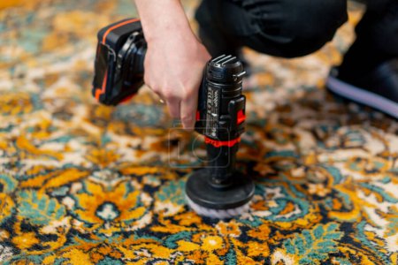 Foto de Primer plano en el apartamento un limpiador maestro limpia la alfombra con detergente utilizando un destornillador y un cepillo - Imagen libre de derechos
