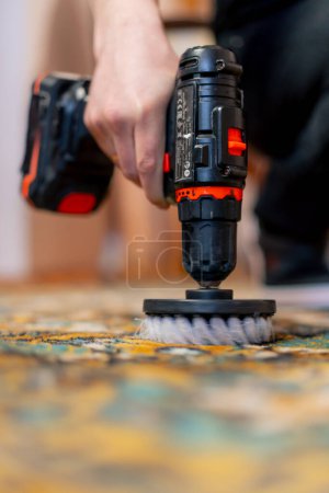 Photo for Close up in the apartment a master cleaner cleans the carpet with detergent using a screwdriver and a brush - Royalty Free Image