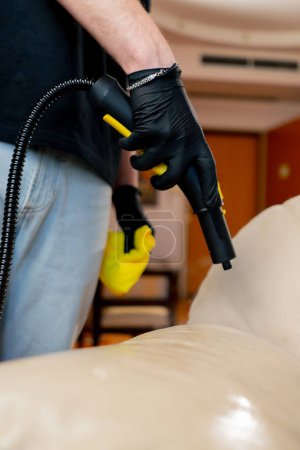 Foto de Cerrar una limpieza profesional del limpiador de apartamentos humeante la piel en el sofá muebles de limpieza - Imagen libre de derechos
