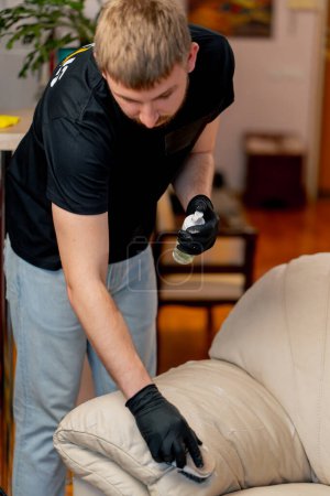 Foto de La limpieza profesional del apartamento el limpiador pule el sofá de cuero con el abrillantador - Imagen libre de derechos