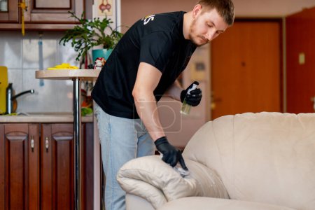 Foto de La limpieza profesional del apartamento el limpiador pule el sofá de cuero con el abrillantador - Imagen libre de derechos