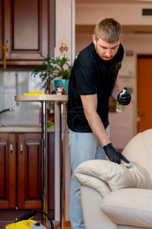 Téléchargez les photos : Nettoyage professionnel d'un appartement un nettoyeur polit un canapé en cuir avec du vernis - en image libre de droit
