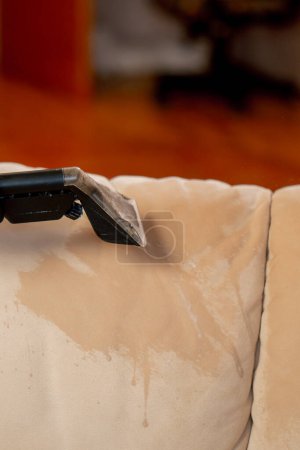 Foto de Cerca de limpieza profesional en un apartamento un limpiador moja un sofá textil antes de lavar - Imagen libre de derechos