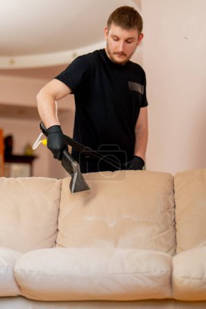 Foto de Limpieza profesional en un apartamento un limpiador moja un sofá textil antes de lavar - Imagen libre de derechos
