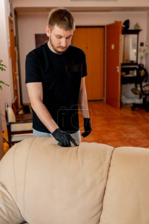 Téléchargez les photos : Nettoyage professionnel dans un appartement le nettoyant nettoie le canapé textile avec une brosse et un détergent - en image libre de droit