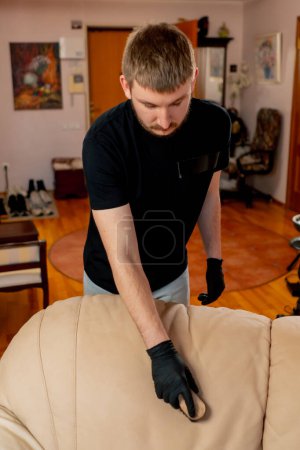 Foto de Limpieza profesional en un apartamento el limpiador limpia sofá textil con un cepillo y detergente - Imagen libre de derechos
