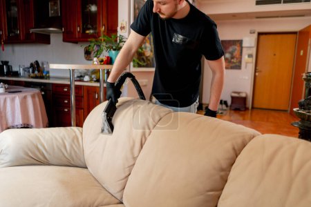Foto de Limpieza profesional del limpiador de apartamentos aspirando con detergente sofá textil - Imagen libre de derechos