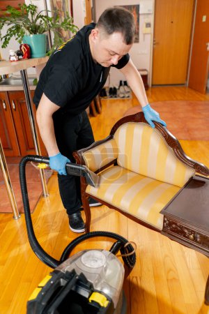 Téléchargez les photos : Nettoyage professionnel d'un appartement un nettoyeur mouille la console avant de laver - en image libre de droit