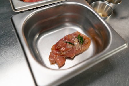Téléchargez les photos : Gros plan d'un morceau de filet de poulet cru dans une cuisine professionnelle dans un bol en fer - en image libre de droit