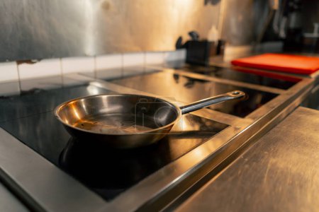 Photo for Close-up of a small frying pan for frying meat being heated on professional stove - Royalty Free Image