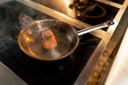Photo for In a professional kitchen a piece of chicken fillet is fried in a small frying pan - Royalty Free Image
