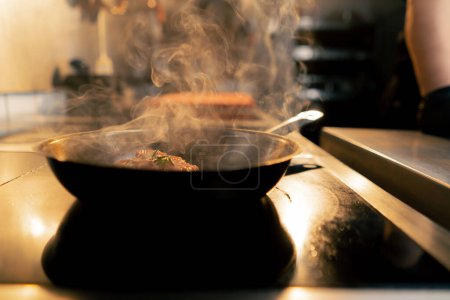 Photo for Close up in a professional kitchen a piece of chicken fillet is fried in a small frying pan - Royalty Free Image