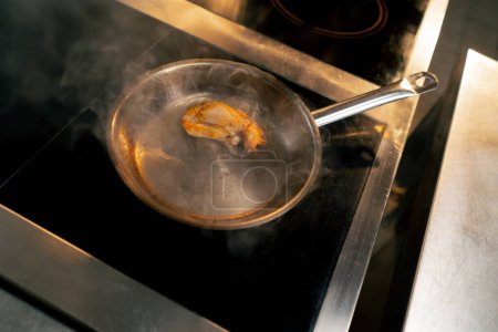 Photo for Top shot close up in a professional kitchen a piece of chicken fillet is fried in a small frying pan - Royalty Free Image