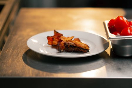 Téléchargez les photos : Close-up dans une cuisine professionnelle sur une assiette blanche se trouve filet de poulet frit pour salade - en image libre de droit