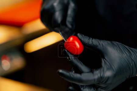 Foto de Primer plano en la cocina profesional el chef corta un tomate cherry con un cuchillo pequeño - Imagen libre de derechos