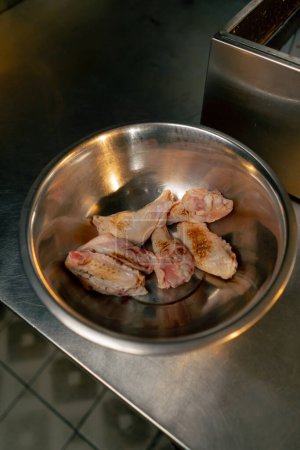 Téléchargez les photos : Close-up dans une cuisine professionnelle dans un bol en fer ailes de poulet sont légèrement frit - en image libre de droit