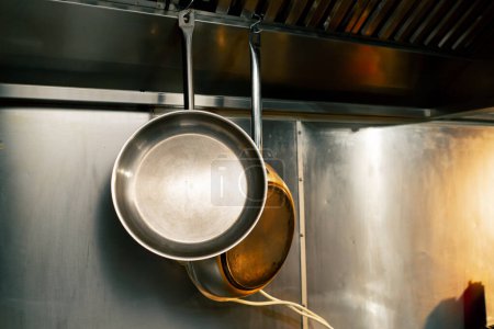 Téléchargez les photos : Close-up dans une cuisine professionnelle deux poêles à frire pèsent sur un support mural pour la friture des aliments - en image libre de droit
