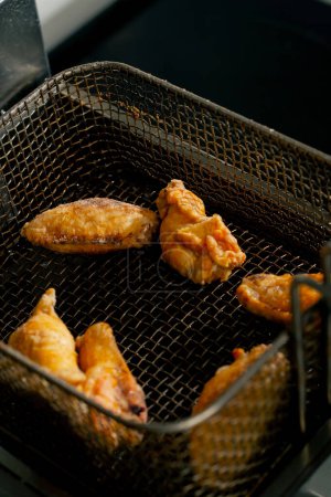 Photo for Close-up in professional kitchen the chef takes out chicken wings from the fryer - Royalty Free Image