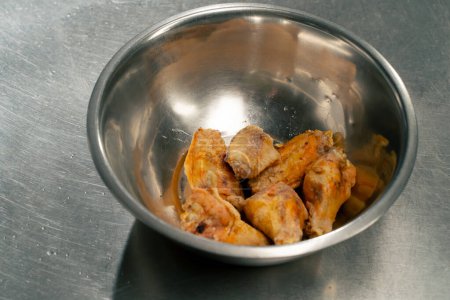 Téléchargez les photos : Gros plan des ailes de poulet de la friteuse dans une cuisine professionnelle dans un bol en fer - en image libre de droit