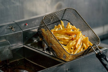 Photo for Close-up in professional kitchen the chef takes out french fries from the fryer - Royalty Free Image