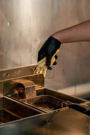 Téléchargez les photos : Gros plan dans une cuisine professionnelle, le chef jette des frites dans la friteuse - en image libre de droit