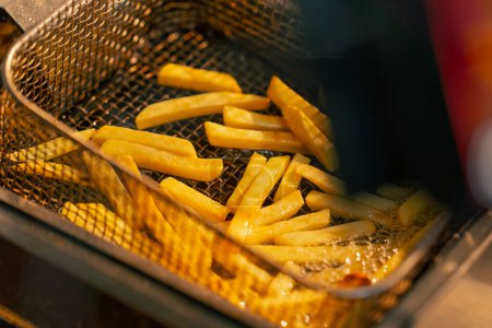 Téléchargez les photos : Gros plan de frites frites dans une cuisine professionnelle dans une friteuse - en image libre de droit