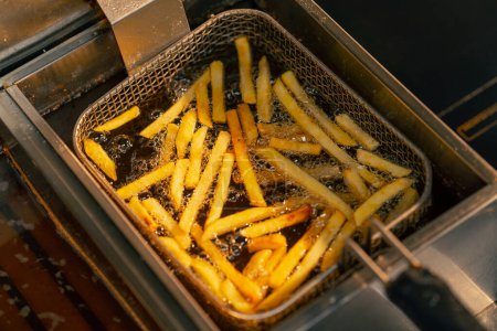 Foto de Primer plano de papas fritas fritas en una cocina profesional en una freidora - Imagen libre de derechos