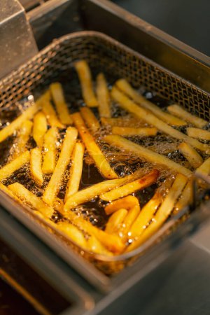 Foto de Primer plano de papas fritas fritas en una cocina profesional en una freidora - Imagen libre de derechos